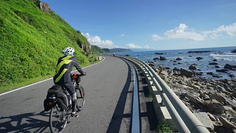 A cyclist rides along a coastal road in Taiwan's Kenting National Park (Credit: Getty Images)