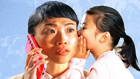 A young girl whispers a word in a woman's ear while the woman is on the phone (Credit: BBC/ Serenity Strull/ Getty Images)