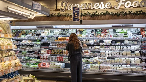 Woman in supermarket looking at refridgerated shelves (Credit: Getty Images)