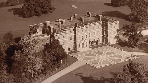 Archival aerial view of Trent Park House, a grand stately home with a flag flying from roof surrounded by grounds, from early 20th Century (Credit: Houghton Hall)