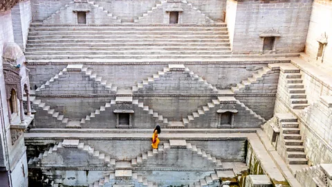 The restored Toorji Ki Jhalara stepwell, filled with water with people sitting around it on the steps (Credit: Alamy)