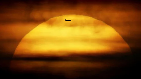 An airplane passes in front of the setting sun in London. A flight does not always divert if someone expires onboard. (Press Association)