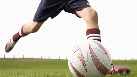 A teenage boy kicking a football