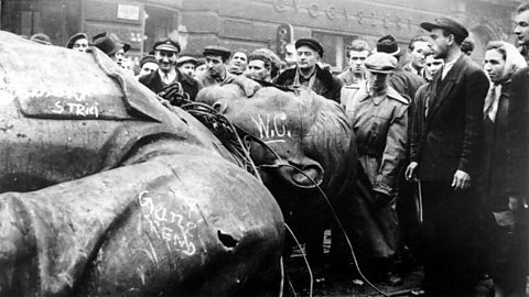  Crowd inspects fallen statue of Stalin.