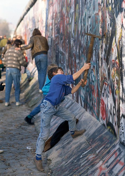 Youth swings pickaxe at Berlin Wall