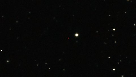 Picture of an ancient gas cloud discovered in 2012 near a quasar 13 billion light-years away, seen here as a faint red dot in the centre.