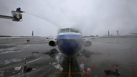 An airport worker sprays de-icing liquid onto a Boeing 737m, as China shivers during snowy winter weather. (Reuters)