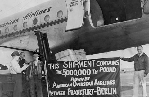 American Airlines cargo plane with four men beside it. Two hold a banner saying 