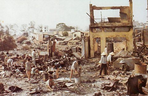 Civilians sorting through rubble of badly damaged buildings