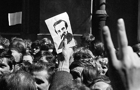 Crowd of people, one of whom holds image of Lech Walesa aloft