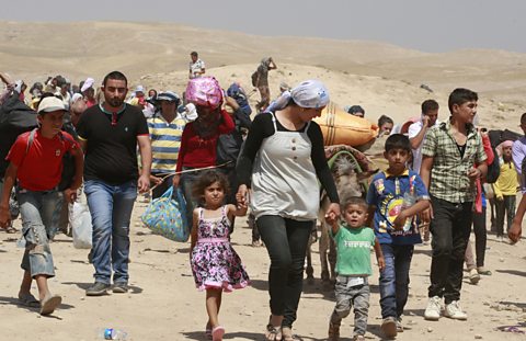 Men, Women and children walking through the desert with all their belongings