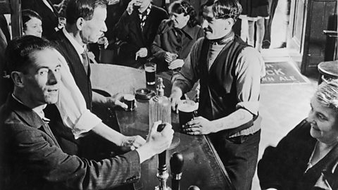 Men and women in a bar in Glasgow in the 1930s. Two children stand in the doorway