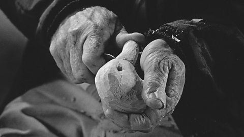 Hands carving wood to make a duck ornament