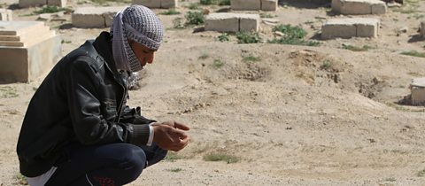 An Iraqi man prays on the tomb of an unknown person at a cemetery in the central city of Karbala.