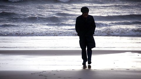 Benjamin Zephaniah walking on a beach.