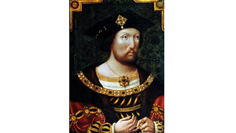 A portrait of Henry VIII as a young man. He is wearing a black hat with a gold and pearl decoration on the front, and a large golden chain across his chest. 