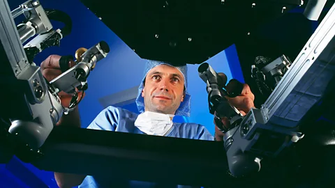 A surgeon controls the Da Vinci robot surgeon, viewing a 3D image of the body (SPL)