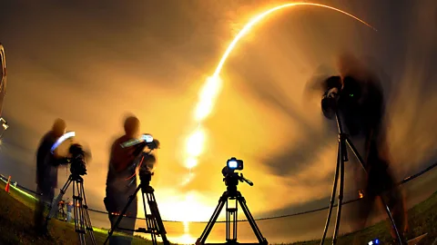 A phalanx of photographers are pictured as the SpaceX Falcon 9 launches from Cape Canaveral, carrying an Asiasat-8 spacecraft to relay TV and broadband signals. (Florida Today/AP)