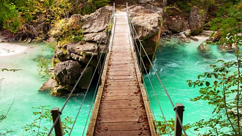 Wooden Ground of a Moving Rope Bridge Over the River with Metallic