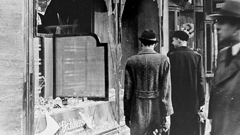 A photograph of two people looking at a broken shop window in Germany