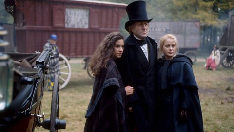 Scene of people standing next to a coach in a field featuring Emma Lewis as Sissy Jupe, Bob Peck as Mr Gradgrind and Beatie Edney as Louisa Gradgrind from 鶹ҳ adaptation of Hard Times (1994).