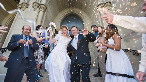 Married couple surrounded by guests throwing confetti over them.