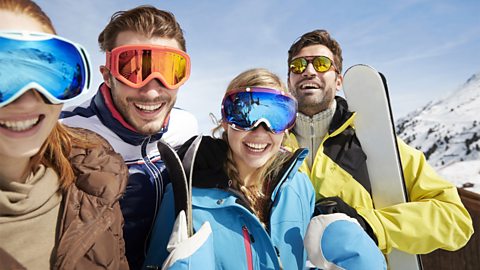 Friends carrying skis on mountain top