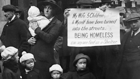 A photo of a destitute family in London in 1919. They are holding a sign asking for help