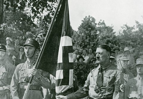 Hitler poses with the "blood flag" from Beer Hall Putsch