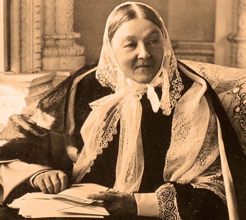 Florence Nightingale photographed in 1885, sat in an arm chair and holding papers.