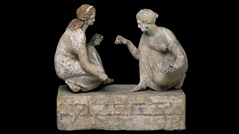 A small statue of two people playing knucklebones.