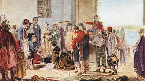 Florence Nightingale on her knees, receiving a wounded soldier at the British hospital in Scutari, with multiple onlookers watching on.