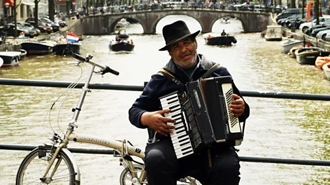 Mark Dadswell/Getty A busker performs from his bicycle in Amsterdam (Credit: Mark Dadswell/Getty)