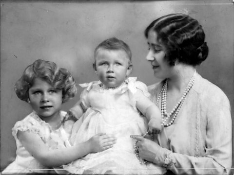 A black and white photograph of Princess Elizabeth and her mother, Queen Elizabeth, with baby Princess Margaret.