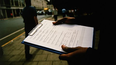 Image of a clipboard and a person taking a survey