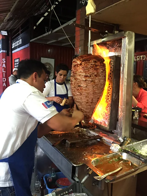 David Farley The taquero shaves off a juicy piece of pork from the trombo (Credit: David Farley)