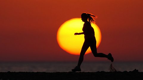 20-year-old woman doing long-distance running on the beach at sunset