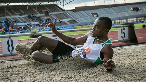 A long jumper lands in the sand