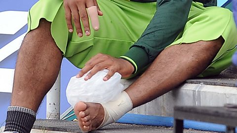 A Pakistani cricketer rests with an ice pack on his ankle after sustaining an injury during a training session