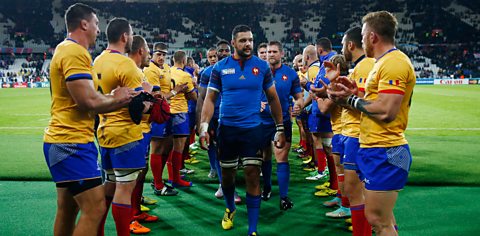 A rugby team in yellow giving their opponents (in blue) a guard of honour by forming two lines and applauding them off the pitch