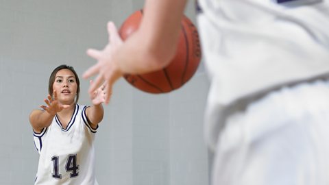 A young female basketballer passes to a team-mate