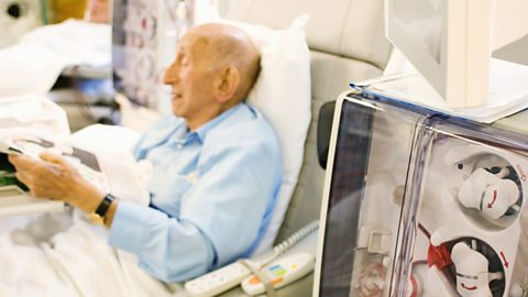 An elderly man receiving treatment in a hospital ward