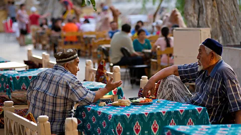 J Marshall - Tribaleye Images/Alamy Men dine at Bukhara’s Lyab-i Hauz square (Credit: J Marshall - Tribaleye Images/Alamy)