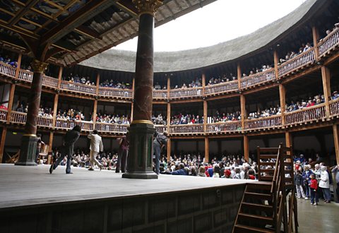 Inside Shakespeare's Globe theatre. Half of the audience are standing to watch the performances.