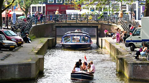 Wim Wiskerke/Alamy People enjoy life along Amsterdam’s famous canals (Credit: Wim Wiskerke/Alamy)