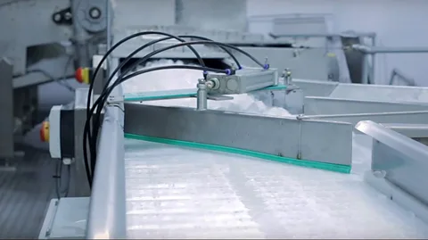 The Ice Co A conveyer belt whisks ice off to be packaged (Credit: The Ice Co)