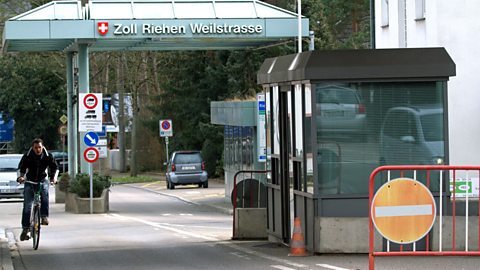 A man on a bicycle enters into Germany from Switzerland at the border crossing