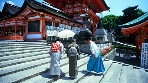 Russell Kord/Alamy People bow outside of a shrine in Kyoto (Credit: Russell Kord/Alamy)