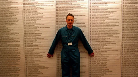 Michael Landy/Parisa Taghizadeh Landy stands in front of the exhaustive catalogue of his 7,227 of his belongings – in the end all that remained was his blue boiler suit (Credit: Michael Landy/Parisa Taghizadeh)