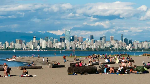 David Pearson/Alamy People relax on a beach with a view of the downtown Vancouver skyline (Credit: David Pearson/Alamy)